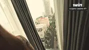 пристает к подруге у окна  небоскреба